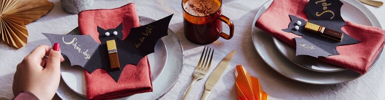 Schwarze Papierfledermäuse auf Servietten.